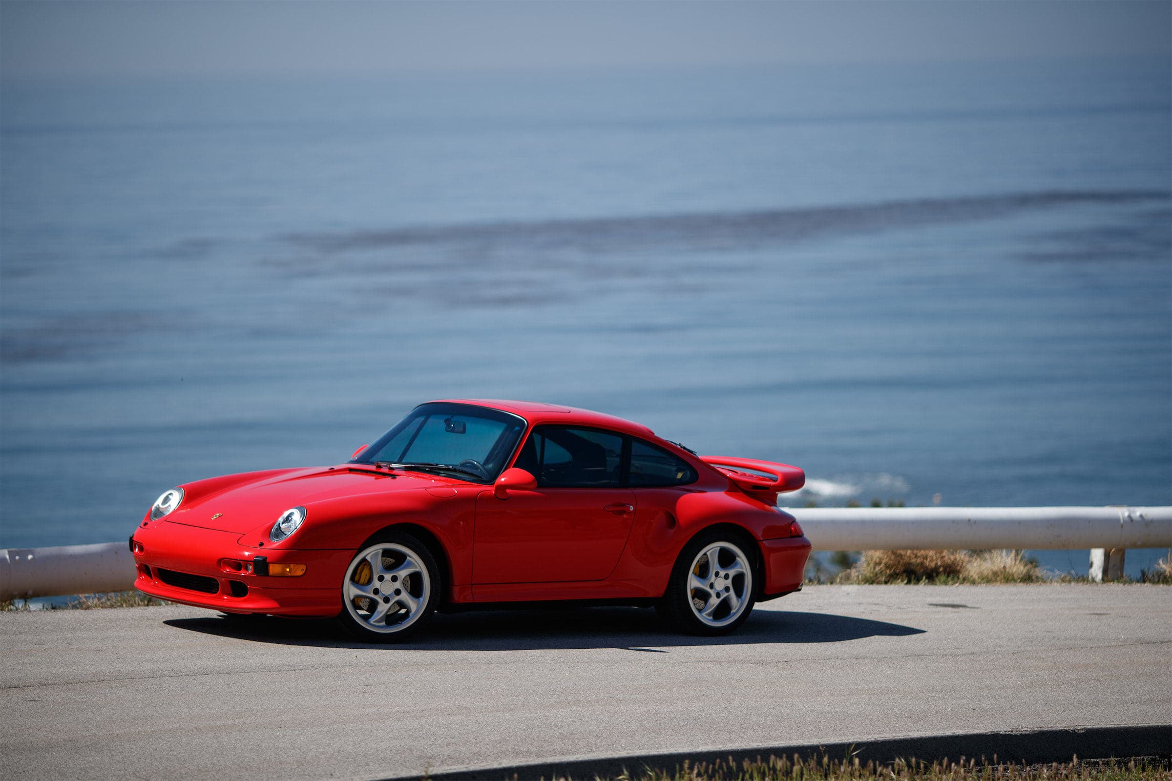Red Porsche 993 Turbo S parked in profile above the Pacific